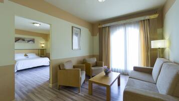 A hotel room with a bed, two sofas, a coffee table, and a lamp.