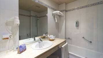 A bathroom with two sinks, a mirror, a towel rack, a hairdryer, and a soap dispenser.