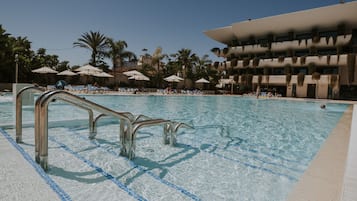 Relax by the pool surrounded by lush greenery and lounge chairs.