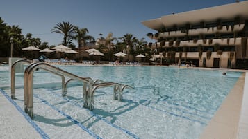 Una piscina cubierta, sombrillas, tumbonas