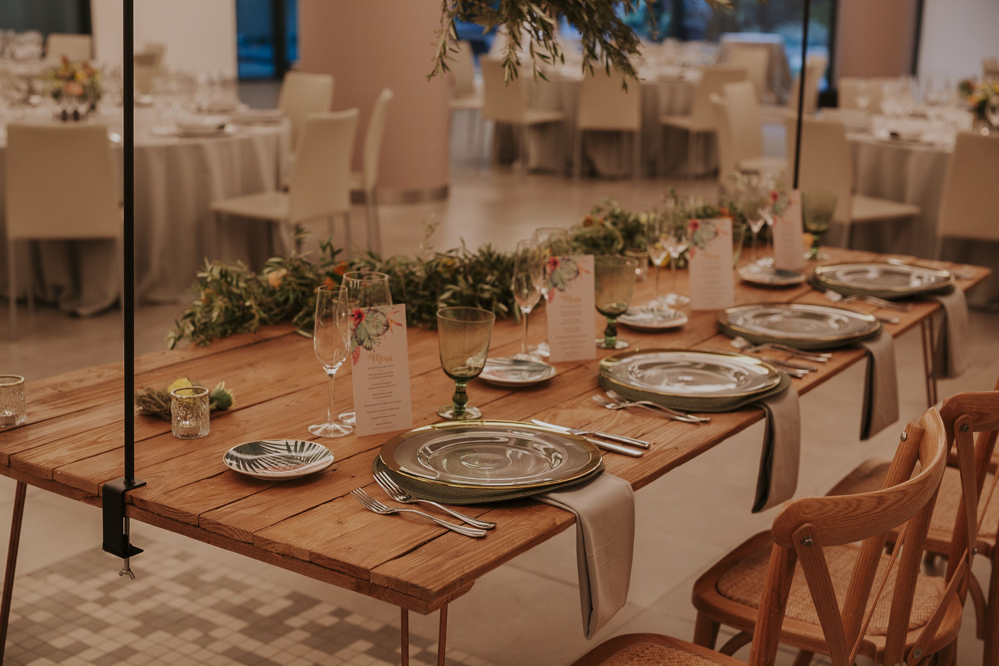 Een lange houten tafel gedekt voor een formeel evenement, met meerdere zitplaatsen, waaronder borden, bestek en glazen, gerangschikt in een banketopstelling.