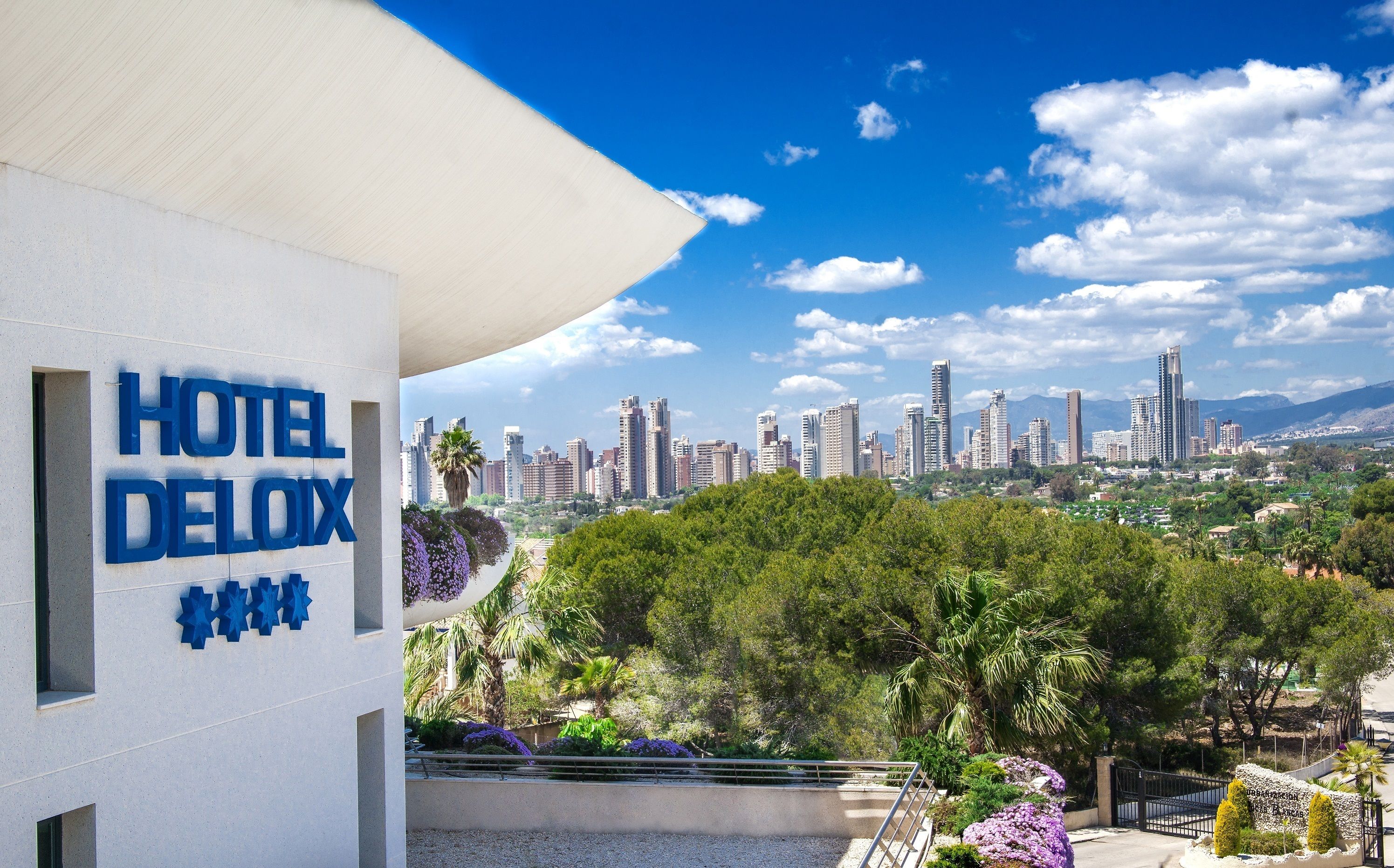 Un hôtel appelé HOTEL DELUXE, offrant une vue sur les toits de la ville et la verdure environnante.