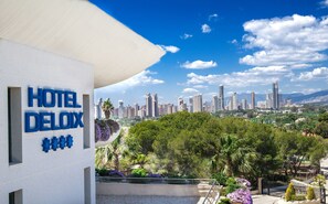 Un hotel llamado HOTEL DELUXE con vistas a un horizonte urbano y zonas verdes circundantes.