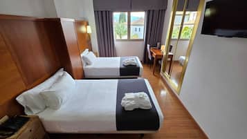 Een hotelkamer met twee bedden, een bureau, een stoel, een televisie en een grote spiegel.