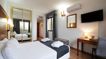 Una habitación de hotel con una cama, un escritorio, una silla, un televisor y un espejo.