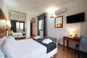 A hotel room with a bed, a desk, a chair, a television, and a mirror. - Hotel Saylu (Granada)