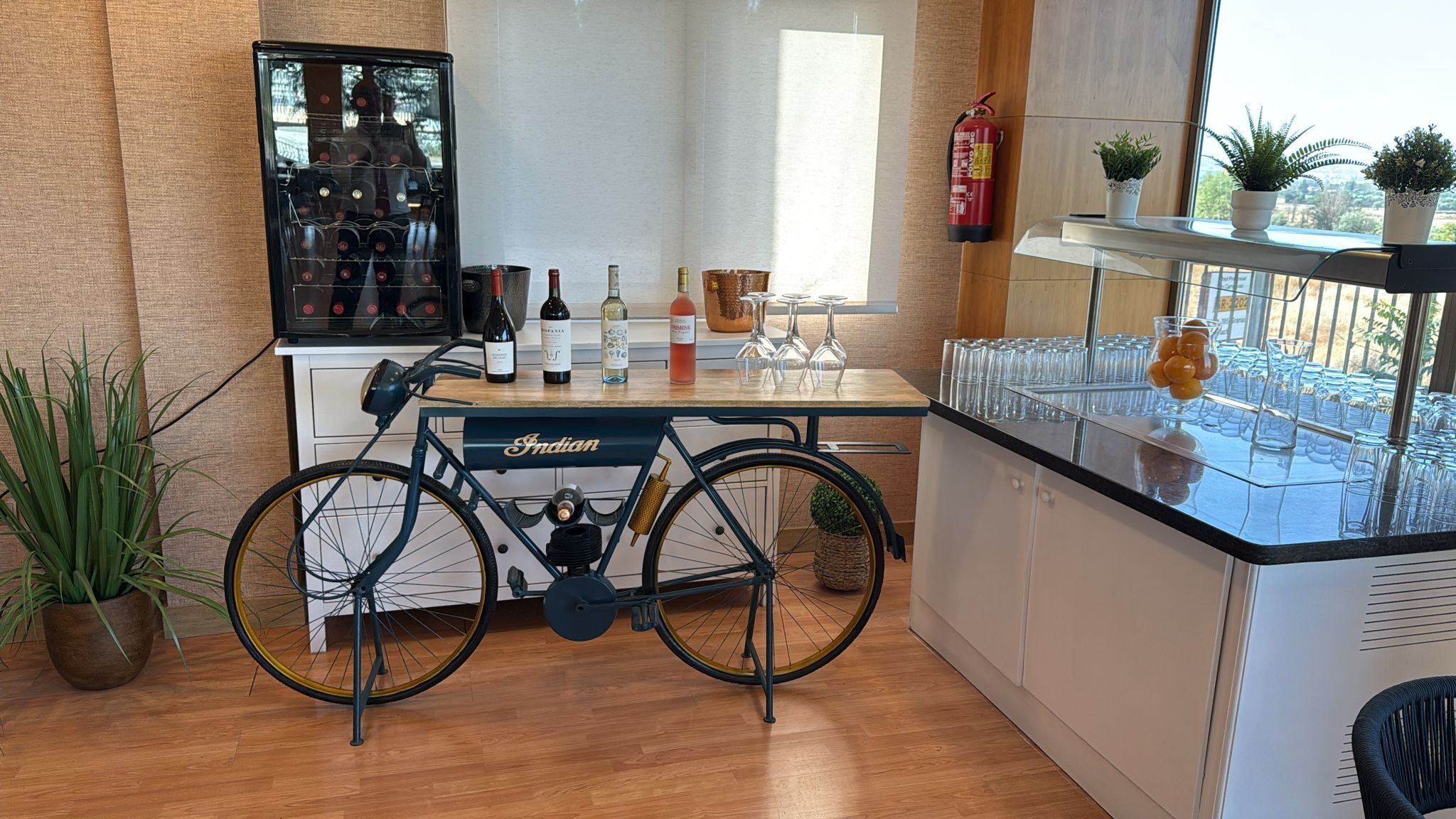 Una cocina con bicicleta, botellas de vino, vasos y un extintor.