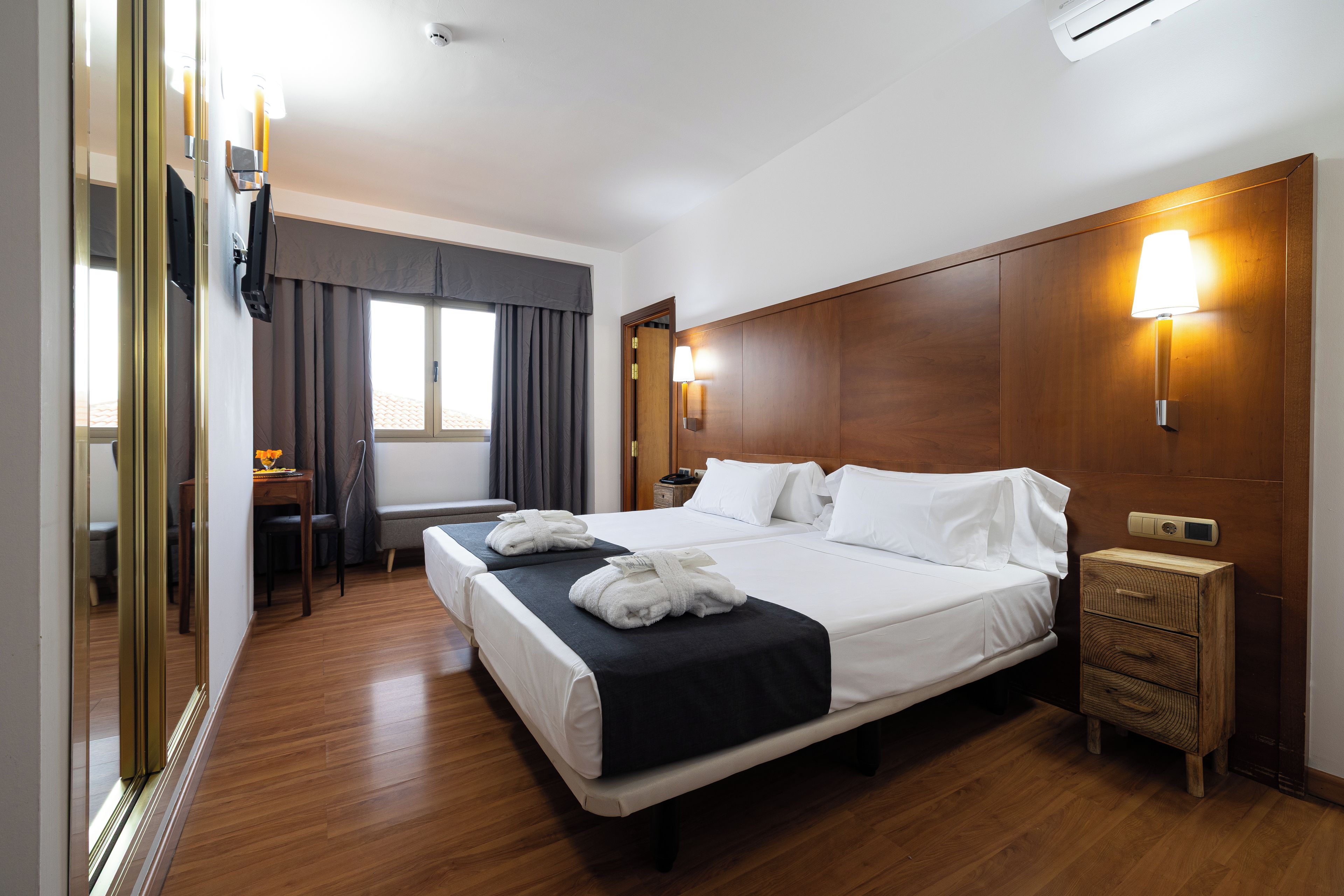 A hotel room with a double bed, bedside tables, a desk, and a chair.
