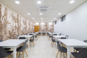 A conference room with white tables and chairs, a patterned mural on the walls, and a ceiling with recessed lighting. - Hotel Saylu (Granada)