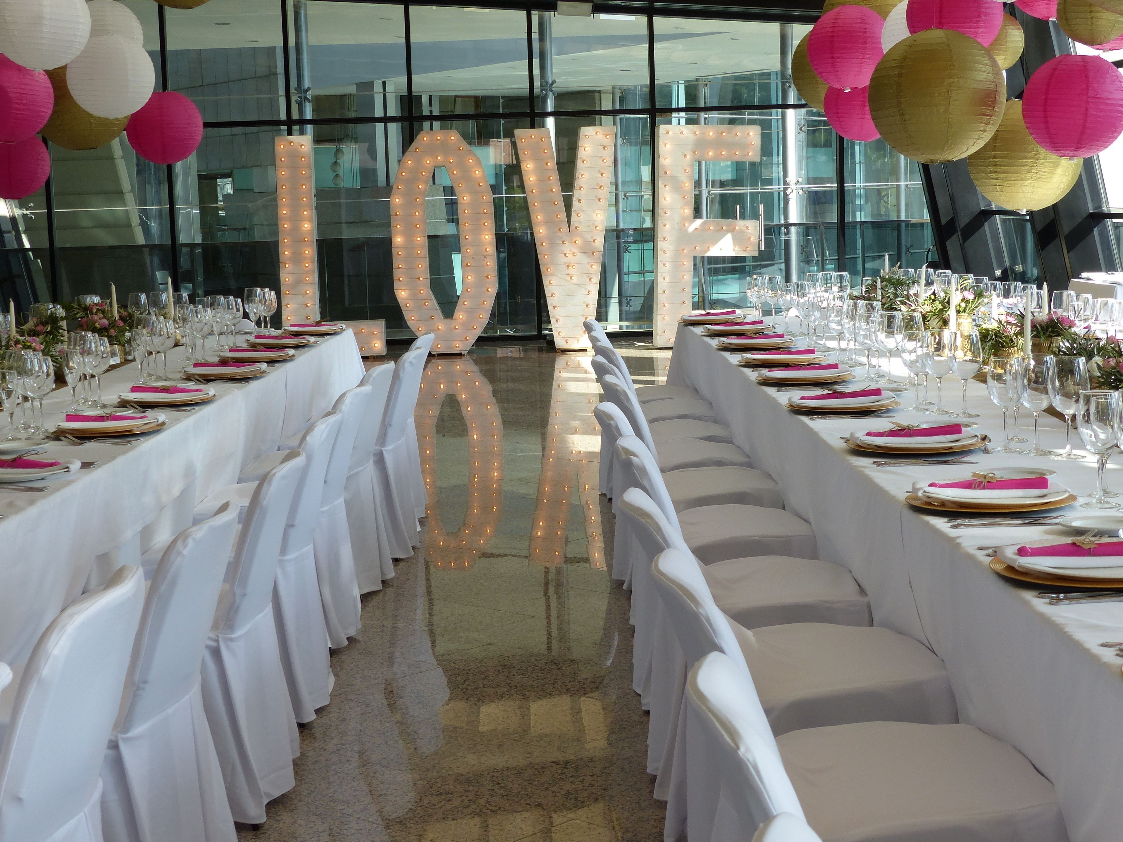 A long banquet table set for a formal event, with white tablecloths, neatly arranged plates, and glasses.