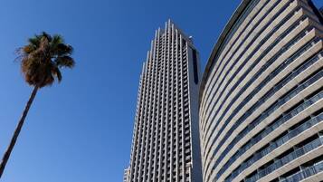 Un edificio alto y moderno con fachada de entramado y una estructura curva a la derecha.