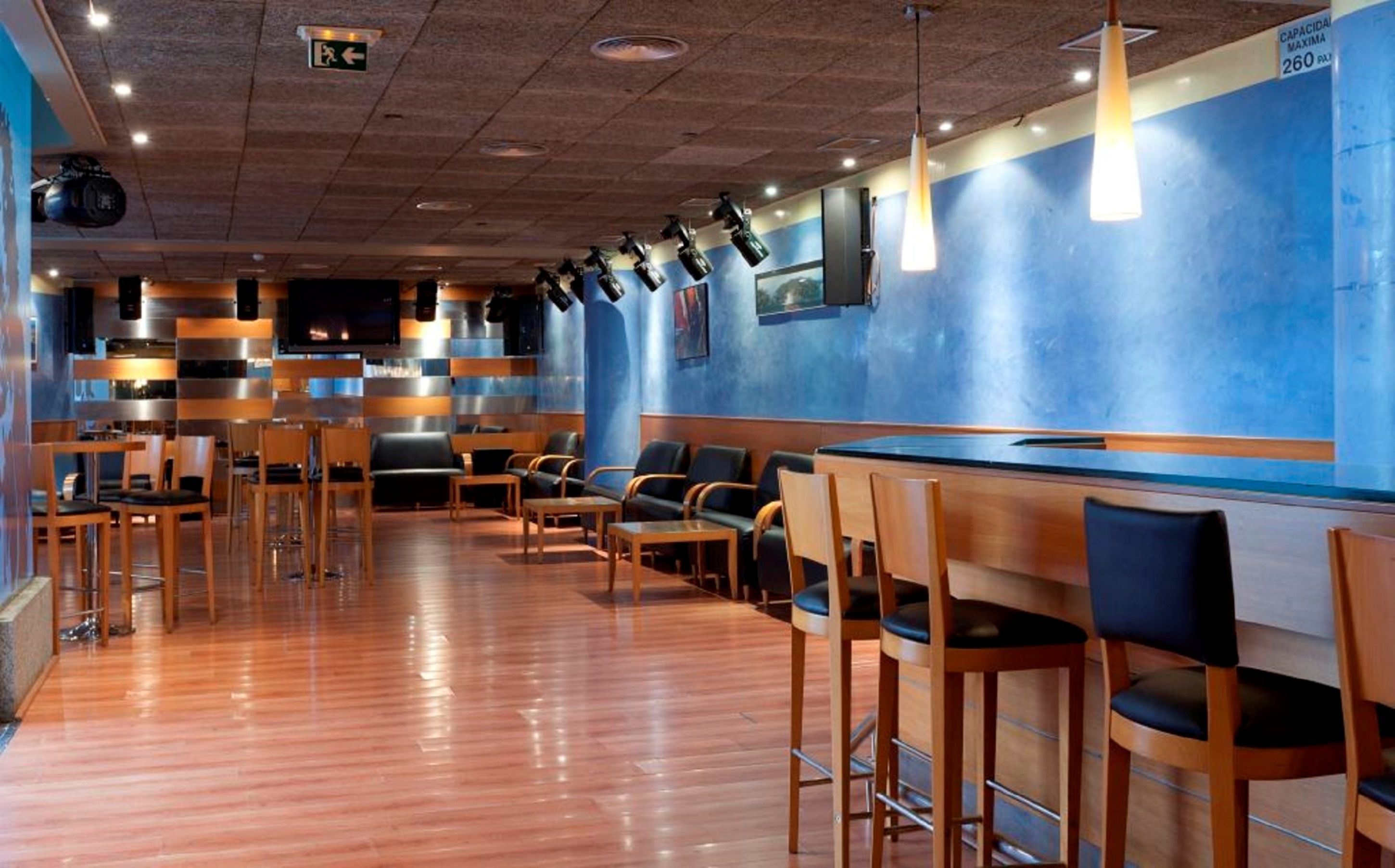 Un restaurante con barra, sillas de madera y pared azul.