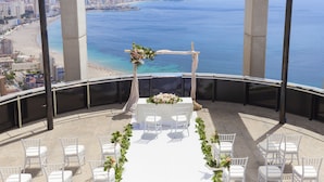 An outdoor wedding setup with a view of the beach and cityscape. - Gran Hotel Bali (Benidorm)