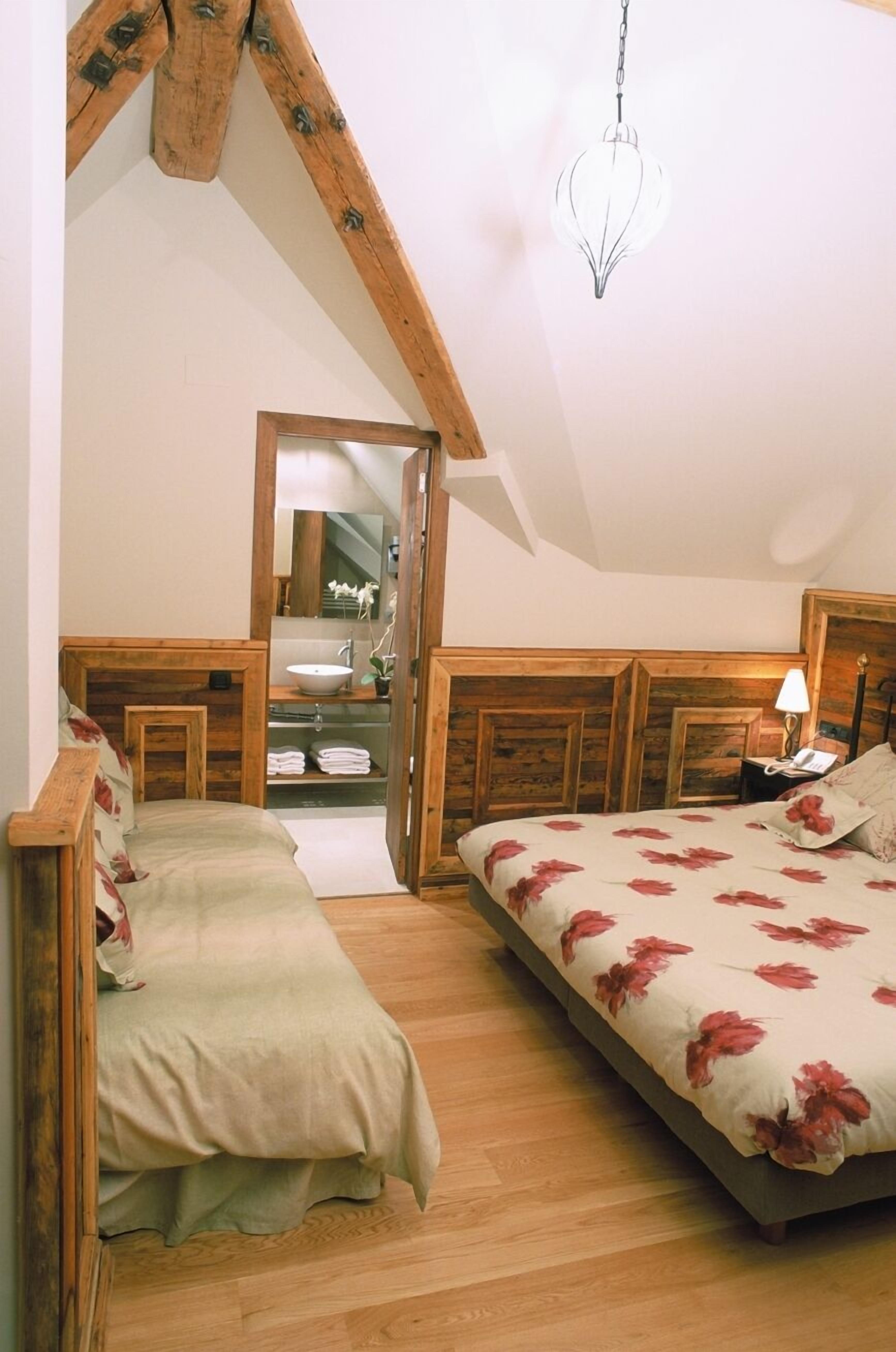 Un dormitorio con cabecera de madera, cama con ropa de cama floral, mesita de noche con lámpara y lámpara colgante.