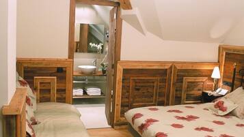 Un dormitorio con cabecera de madera, cama con ropa de cama floral, mesita de noche con lámpara y lámpara colgante.