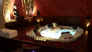 Wellnessbereich mit Whirlpool, Kerzen und einer Buddha-Statue.