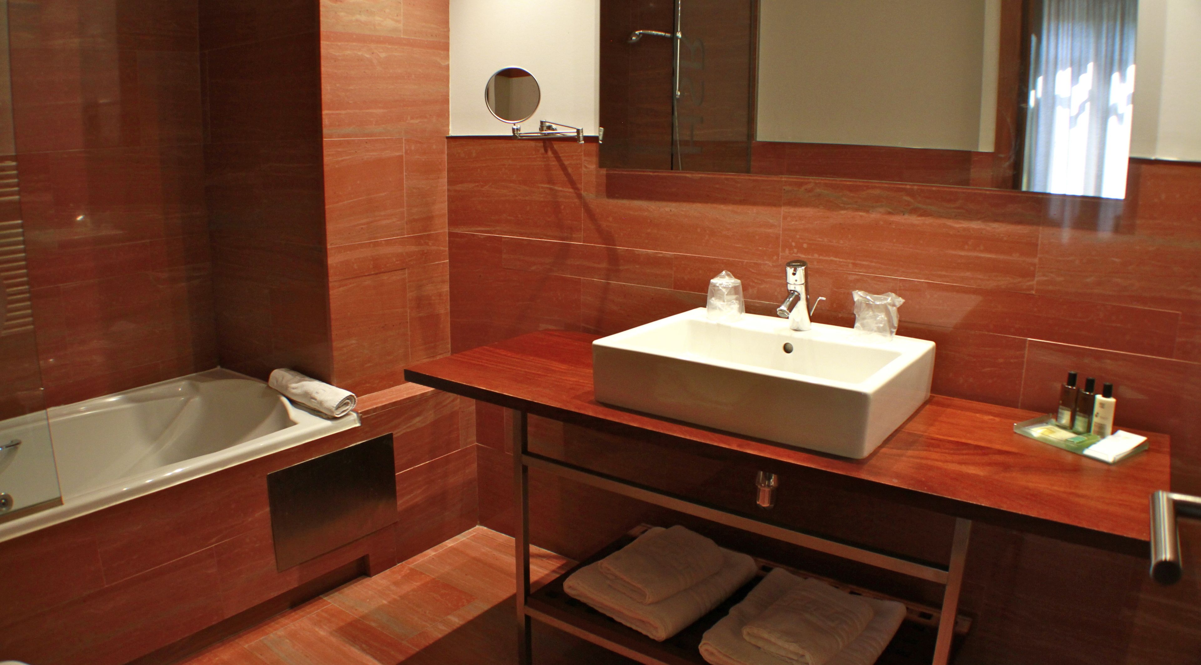 Un baño moderno con lavamanos blanco, espejo y bañera.