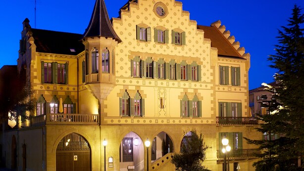 Ein historisches Gebäude mit einer symmetrischen Fassade, zahlreichen Fenstern mit Fensterläden und einem zentralen Turm.
