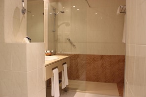 A modern bathroom with a glass-enclosed shower, a vanity with a sink, and a mirror. - Ejido Hotel (El Ejido)
