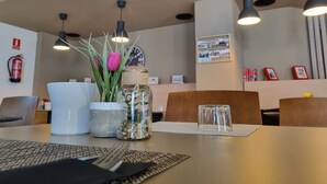 A dining area with a table set for two, featuring a white bowl, a glass jar with a plant, and a clear glass. - Ejido Hotel (El Ejido)