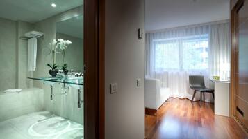 Un baño moderno con lavamanos de vidrio, azulejos blancos y zona de ducha.