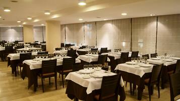 A restaurant with multiple tables set for dining, each with white tablecloths and neatly arranged glassware.