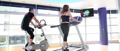 A gym with treadmills and exercise bikes, large windows, and a modern design.