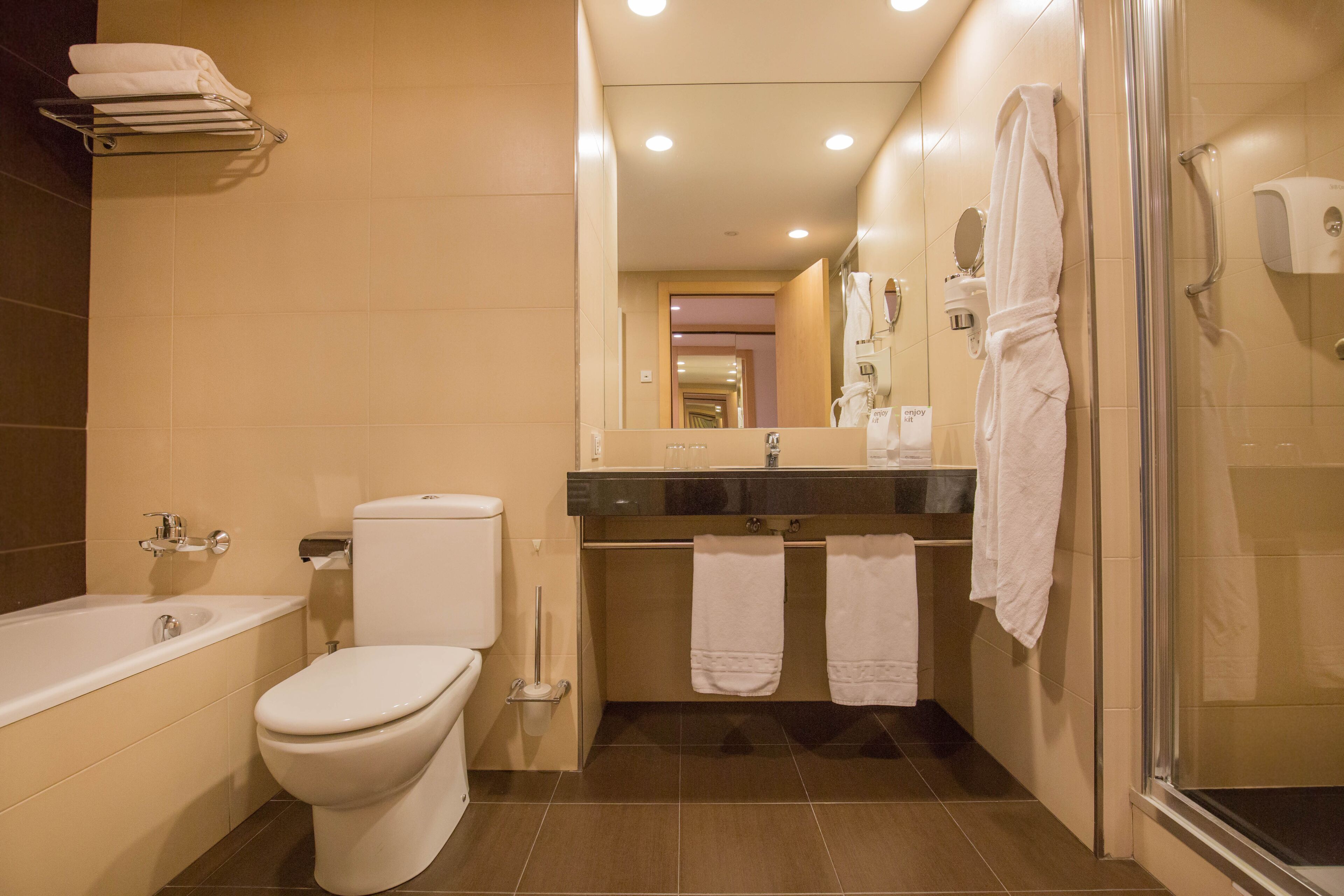 A modern bathroom with a bathtub, toilet, and shower.