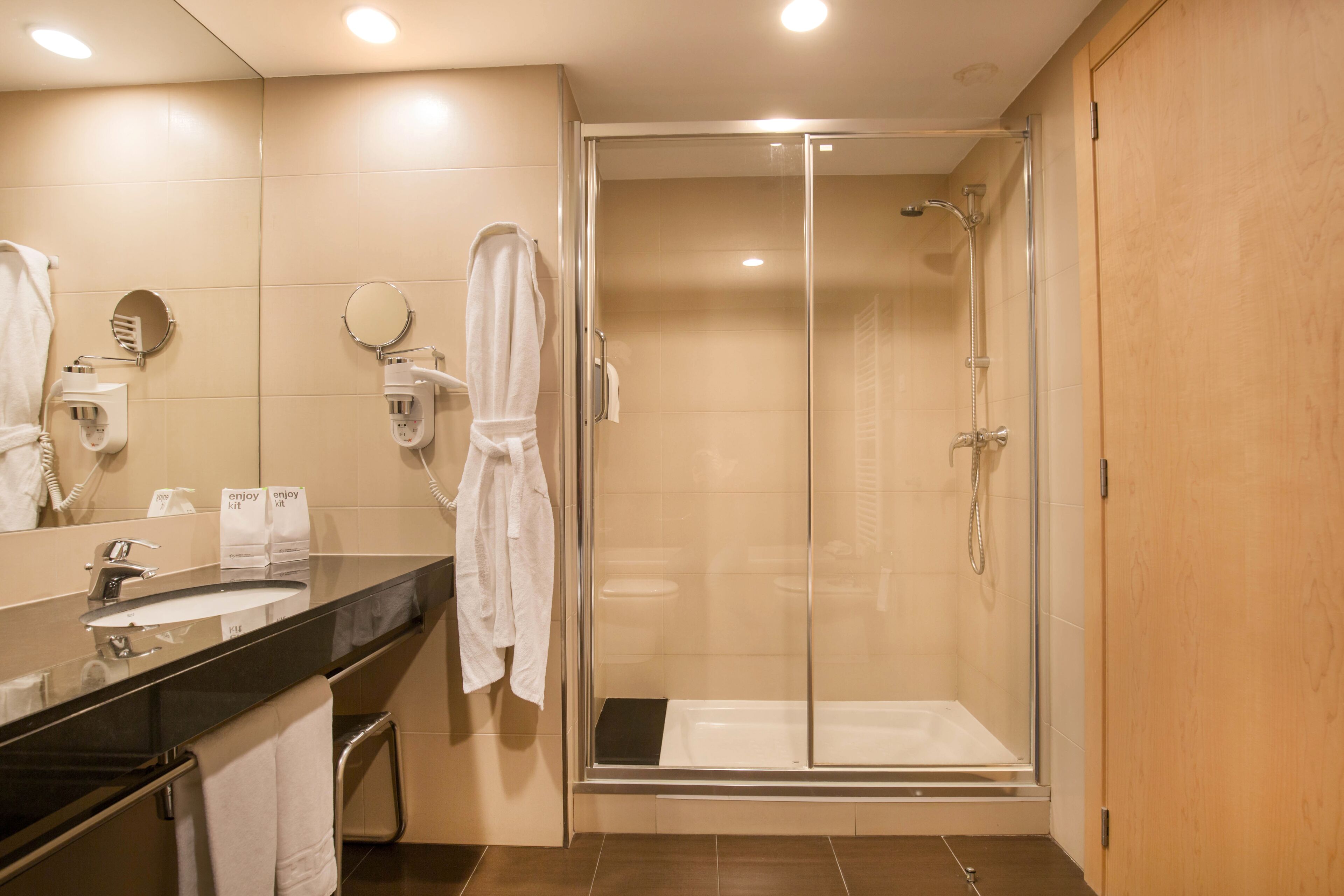 A modern bathroom with a glass-enclosed shower, a sink with a mirror, and a towel rack.