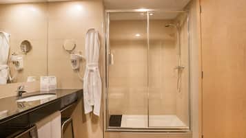 A modern bathroom with a glass-enclosed shower, a sink with a mirror, and a towel rack.
