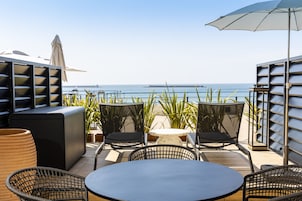 A terrace with outdoor seating, including a round table and chairs, and a large umbrella.