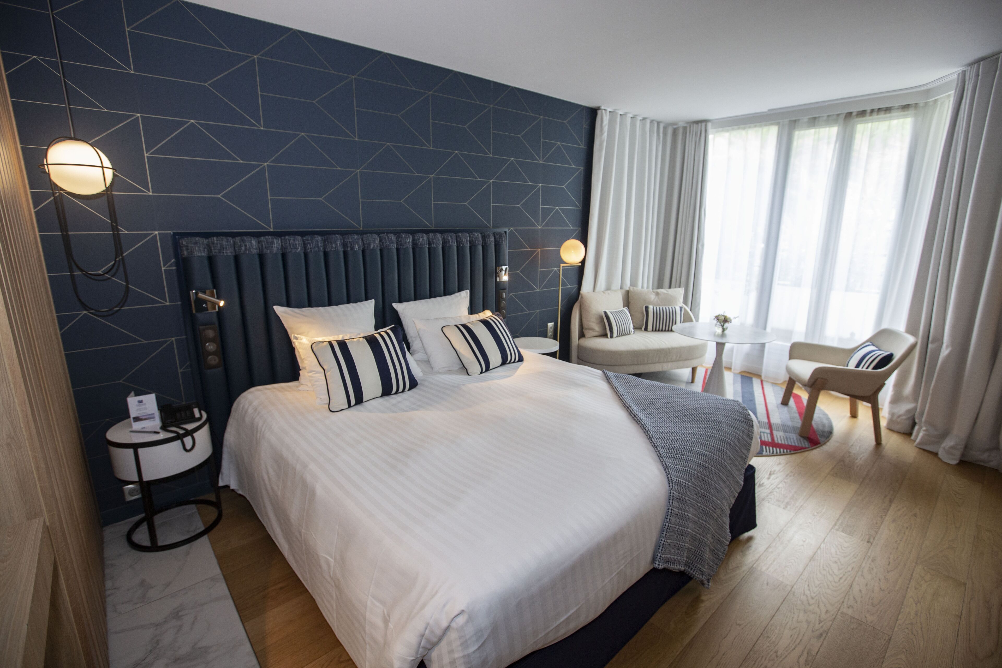 Une chambre d’hôtel moderne avec un grand lit, une table de chevet, une chaise et une petite table.