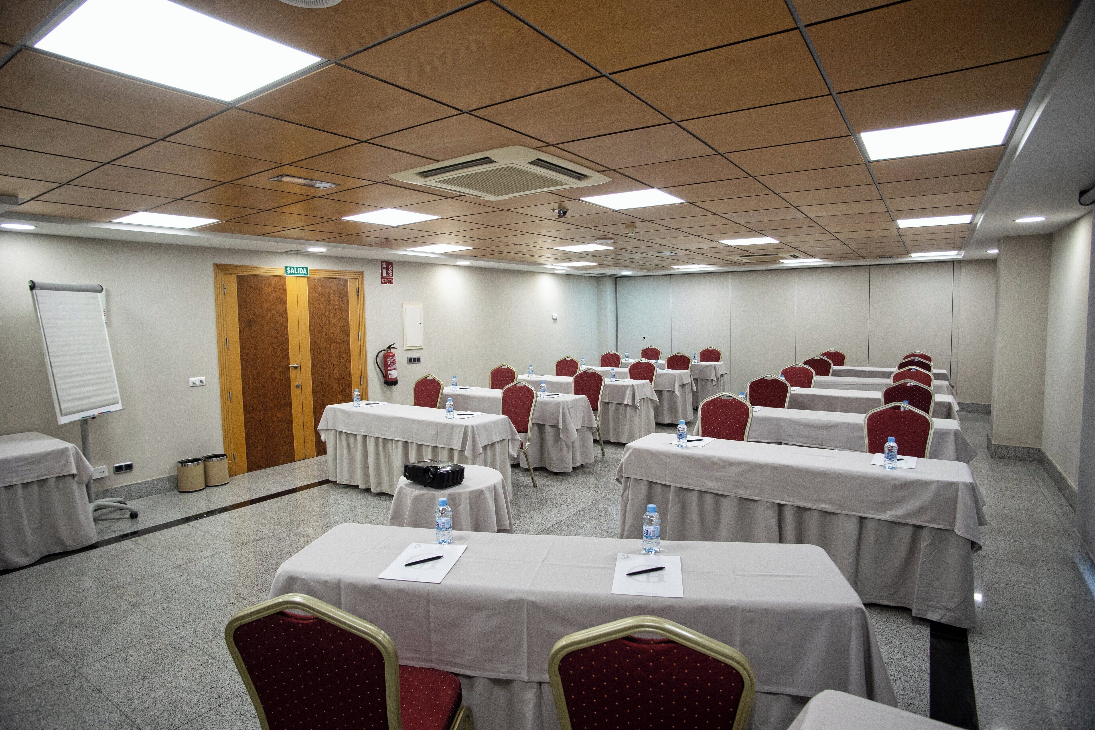 A conference room with multiple tables, chairs, and a whiteboard.