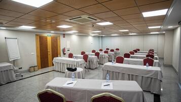 A conference room with multiple tables, chairs, and a whiteboard.