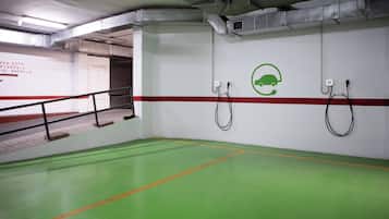 A parking garage with green flooring, a red stripe, and electric vehicle charging stations.