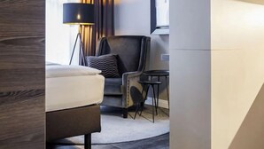 Una habitación de hotel moderna con piso de madera, una cama, un escritorio y una silla.