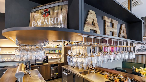 Zona de bar con un cartel de Bacardí y un gran cartel de madera con la palabra 'AHA'.