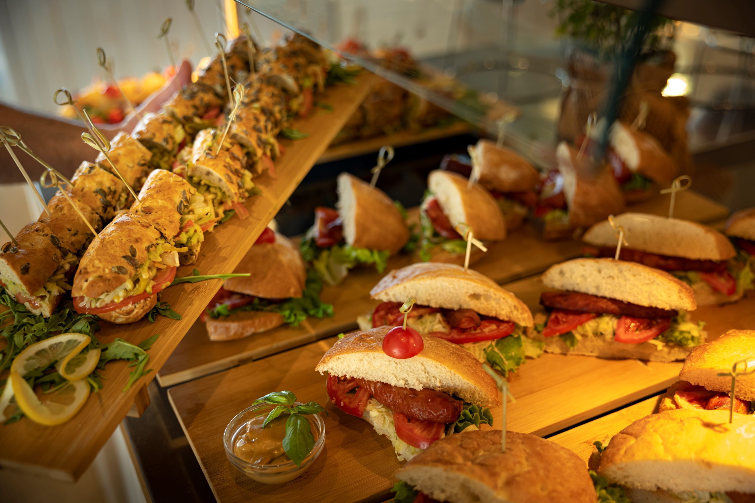 Ein Buffet mit verschiedenen Sandwiches, manche mit sichtbaren Zutaten wie Tomaten und Salat.