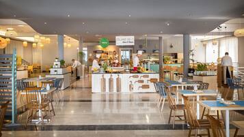 A modern restaurant with a central counter, multiple seating areas, and a variety of food displays.