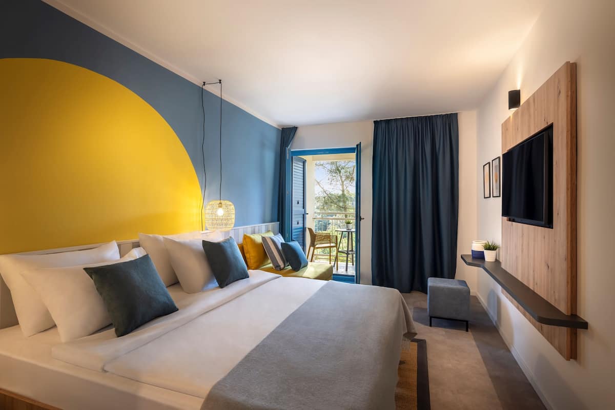 Een moderne hotelkamer met een groot bed, een aan de muur bevestigde televisie en een balkon met uitzicht.