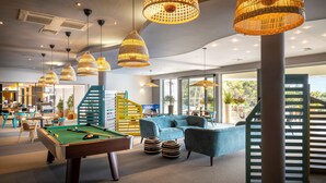 Un salón moderno con mesa de billar, asientos cómodos y ventanas grandes que ofrecen vistas al exterior.