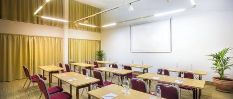 A conference room with multiple tables, chairs, and a projector screen.