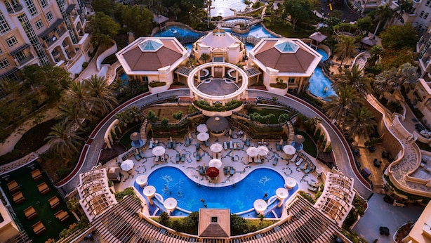 An aerial view of a resort with a central pool, multiple balconies, and lush landscaping. - Swissôtel Al Murooj Dubai (Dubai)