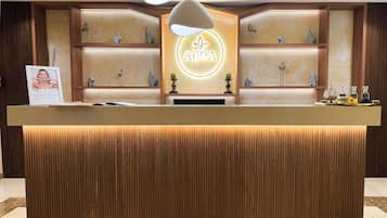 Una recepción con encimera de madera, un letrero de neón y objetos decorativos en estantes.