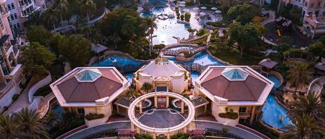 Un resort con varias piscinas, una fuente central y diversas zonas de descanso.