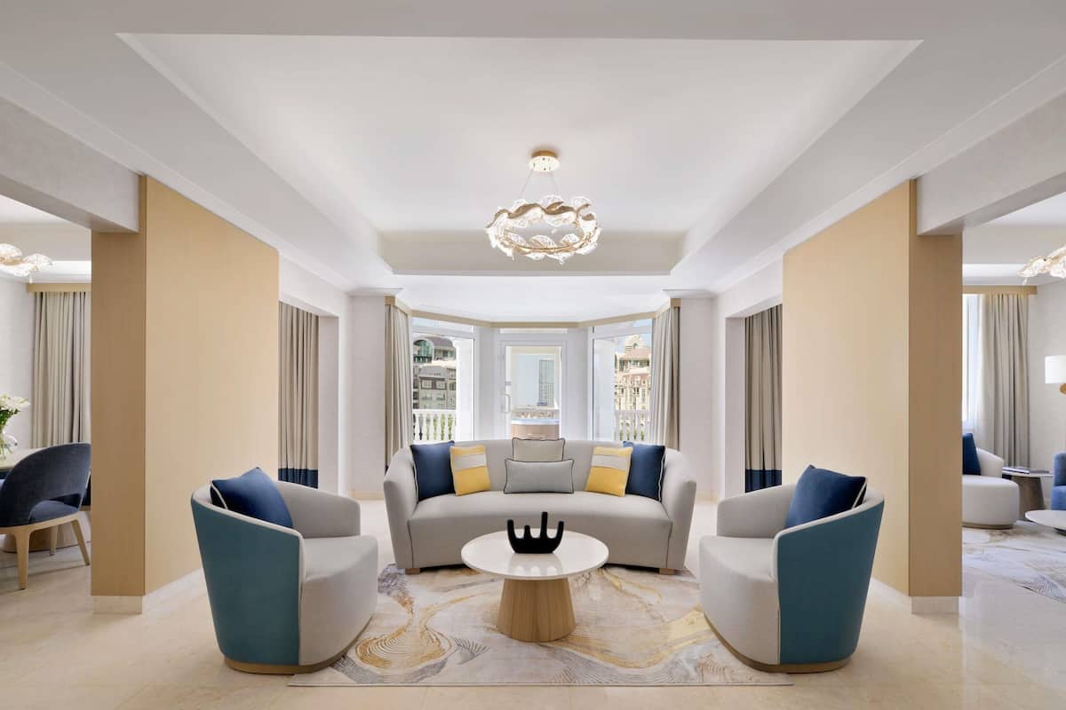 A spacious living room with a sofa, armchairs, a coffee table, and a chandelier.