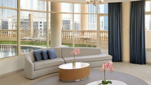 A modern living room with a beige sofa, a round coffee table, and a view of a pool and buildings. - Swissôtel Al Murooj Dubai (Dubai)