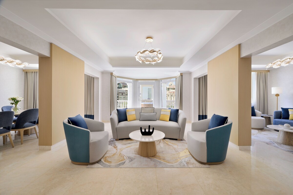 Un salon moderne comprenant un canapé, deux fauteuils, une table basse et un lustre.