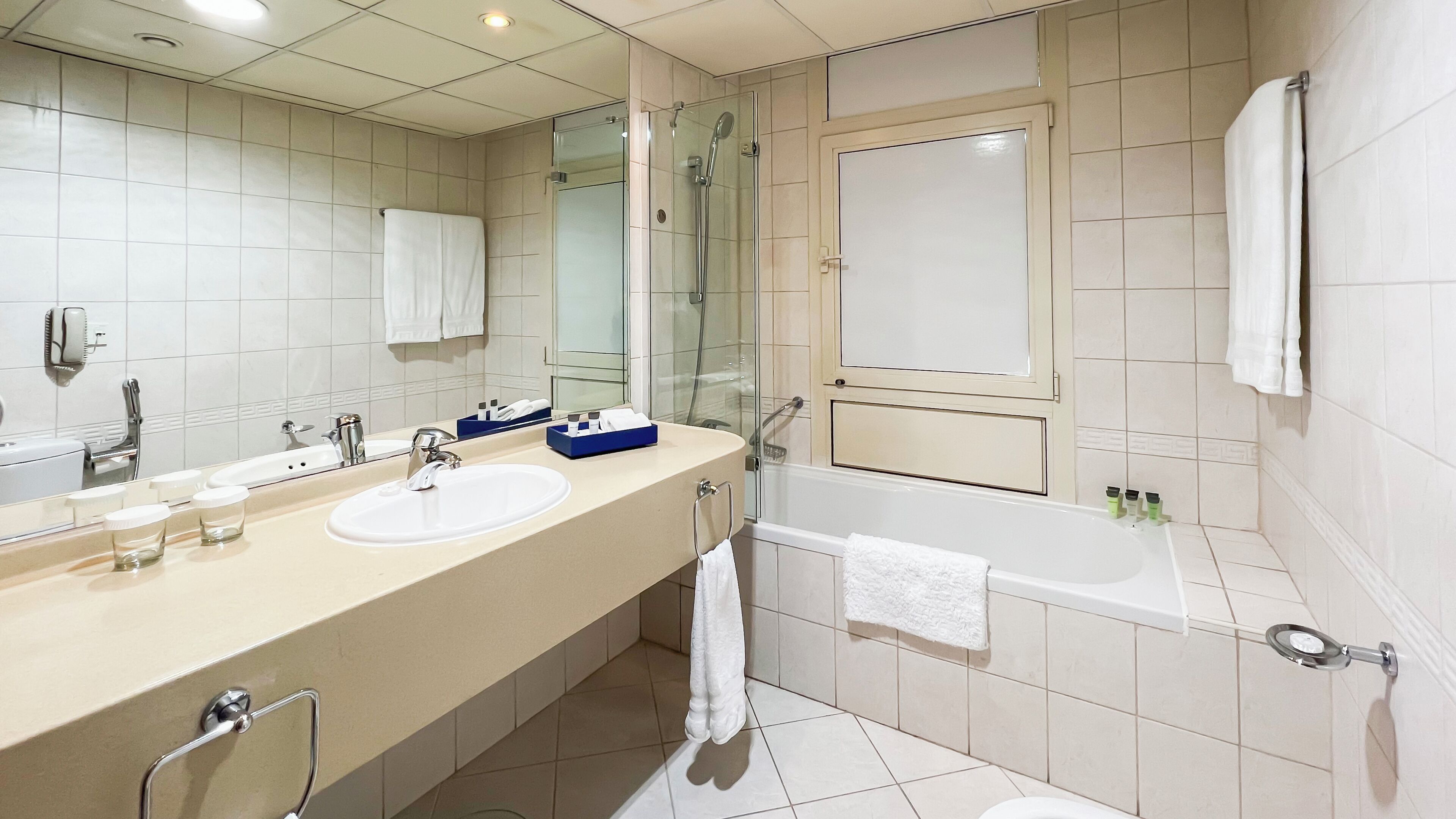 Un baño moderno con un espejo grande, dos lavamanos, ducha y bañera.