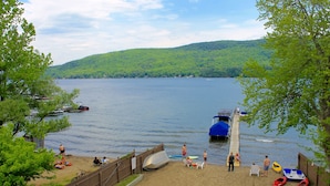 A lakeside beach with boats, chairs, and people. - Sundowner on Lake George (Lake George)